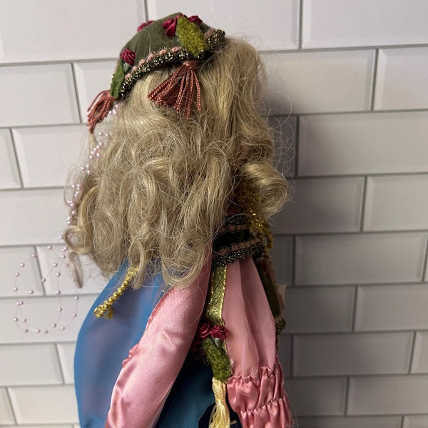 Doll with blonde hair and decorative clothing against a tiled wall