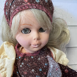 Close-up of a doll with blonde hair and a patterned outfit on a white background