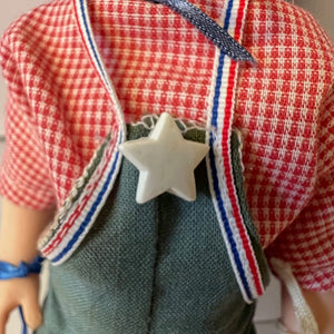 Close-up of a doll with a red checkered shirt and star accessory.