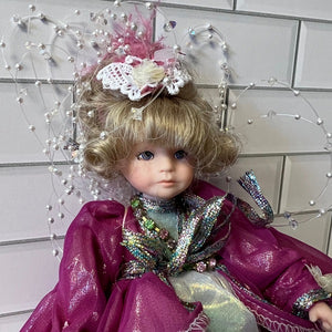 Decorative doll with a pink outfit and headpiece against a tiled wall.