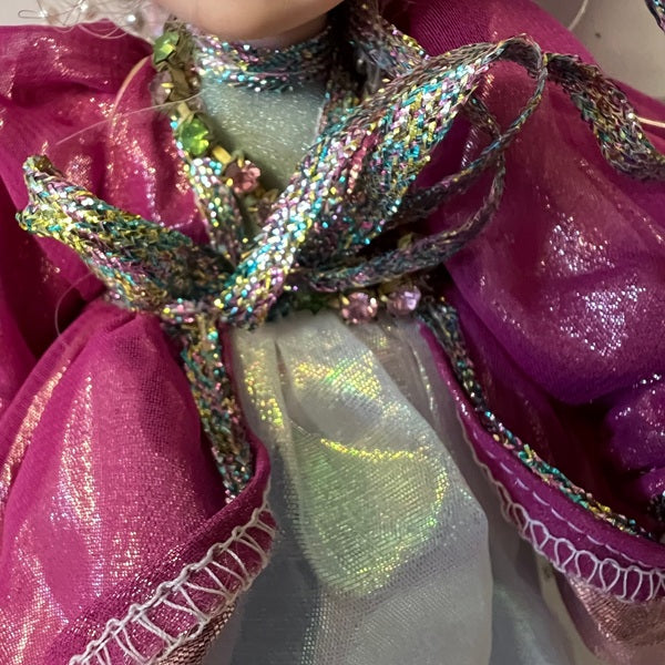 Close-up of a decorative bow with glittery ribbon on a pink fabric background