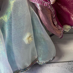 Close-up of a doll wearing a sheer silver skirt.
