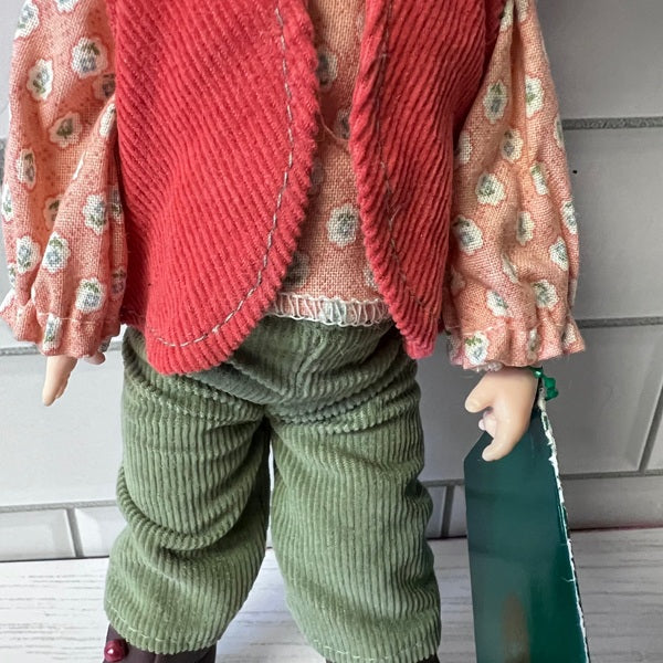 Doll wearing a red floral cardigan and green pants against a neutral background