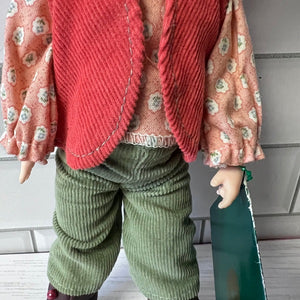 Doll wearing a red floral cardigan and green pants against a neutral background