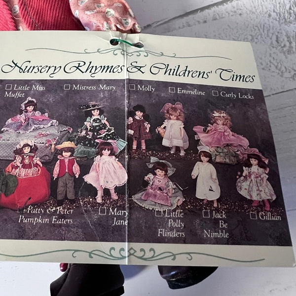 Card with illustrations of dolls and text 'Nursery Rhymes & Children's Times' on a textured surface.