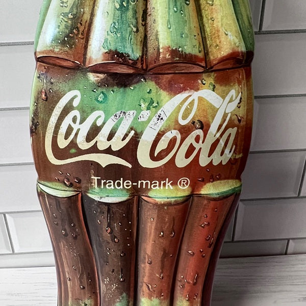 Coca-Cola bottle-shaped decorative item with water droplets on a tiled wall background
