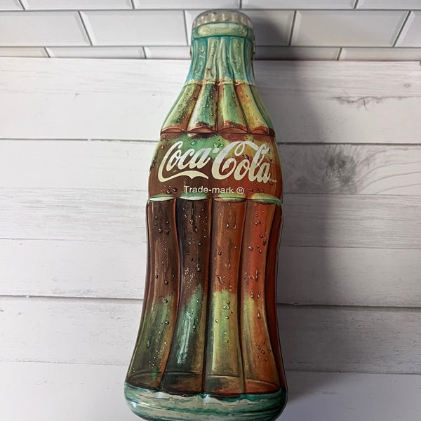 Decorative Coca-Cola bottle wall art on a wooden background