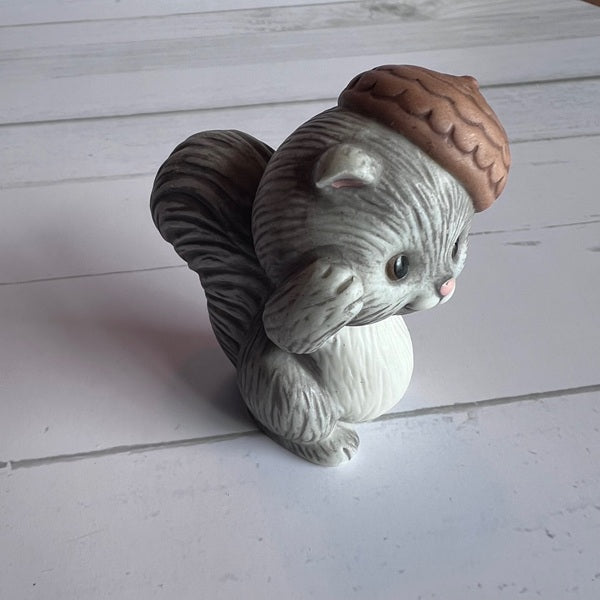Squirrel figurine with a nut on a white wooden surface