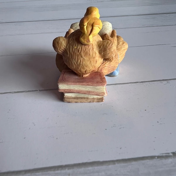Wooden duck figurine on a stack of books against a light wooden background