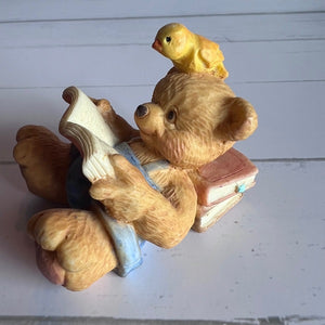 Teddy bear reading a book with a bird on its head against a white background