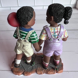 Two children figurines holding hands on a white background