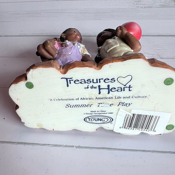 Decorative item with two children and a heart-shaped sign labeled 'Treasures of the Heart' on a white background.
