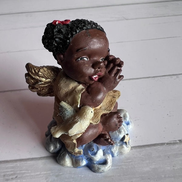 Statue of a child with angel wings and a dove on a white wooden background