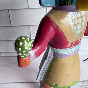 Colorful ceramic figure with a green and white polka dot object on a tiled wall background