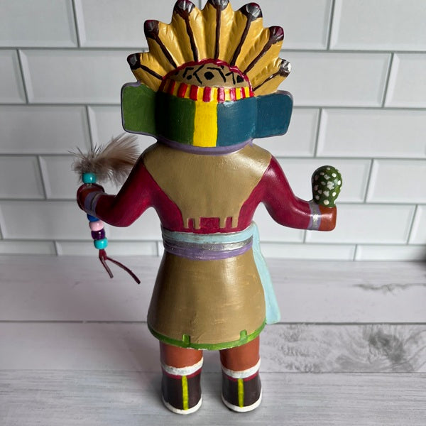 Colorful Native American figurine with headdress on a white tiled background