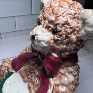 Decorative ceramic figure of a bear with a red bow tie on a white surface.