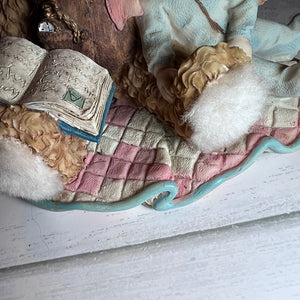 Close-up of a figurine with a book and checkered fabric on a white surface