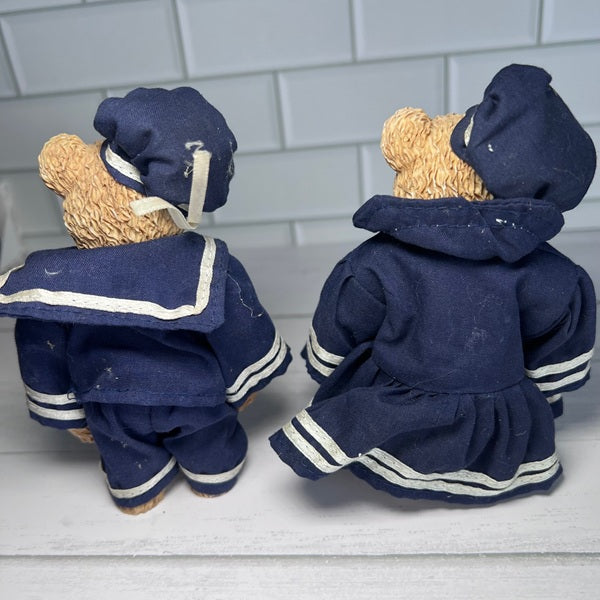 Two teddy bears in navy blue sailor outfits on a light gray tiled background