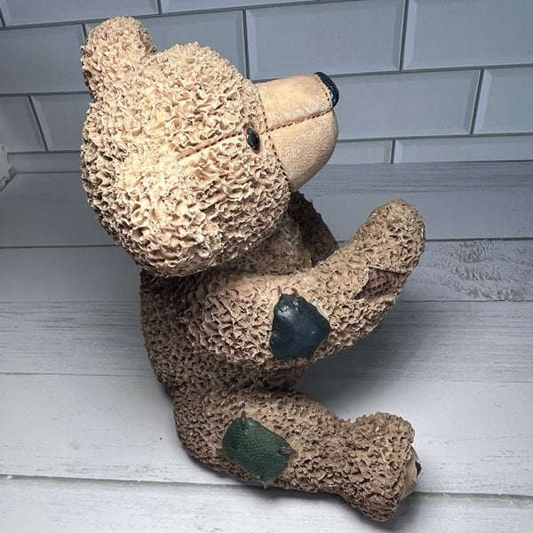 Brown teddy bear with a textured surface on a white wooden floor.