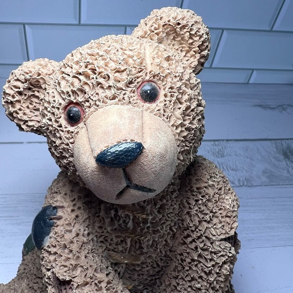 Textured teddy bear with a black nose against a tiled wall background