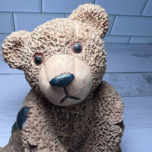 Textured teddy bear with a black nose against a tiled wall background