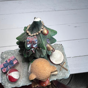 Decorative Christmas tree figurine with ornaments on a white wooden surface
