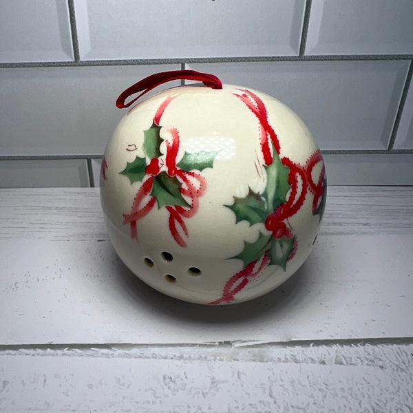 Decorative ceramic ornament with red and green holly design on a white surface.