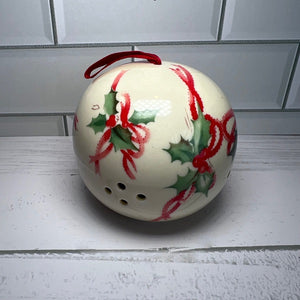 Decorative ceramic ornament with red and green holly design on a white surface.