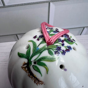 Decorative ceramic pot with floral design and pink triangle on a tiled wall background