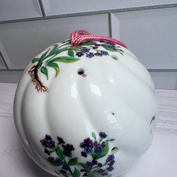 Decorative ceramic ball with floral design and pink string on a tiled wall background
