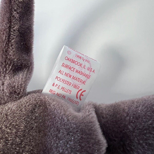 Close-up of a label on a plush toy with text and a brand logo.