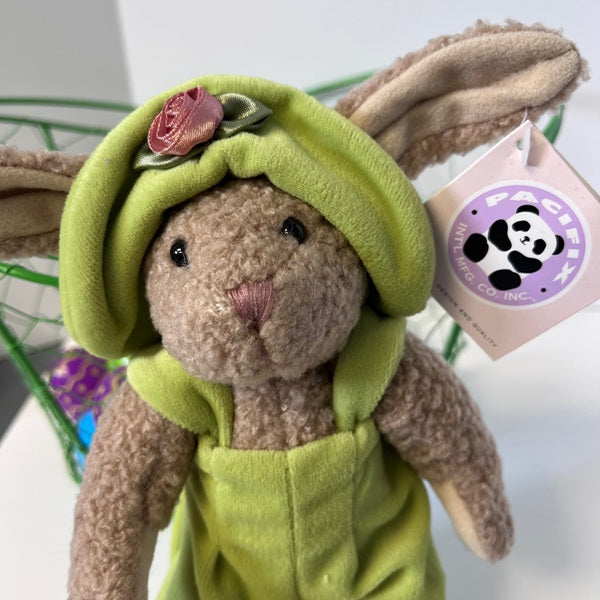 Plush toy rabbit in a green outfit with a flower on its head, branded 'Pacifica'.