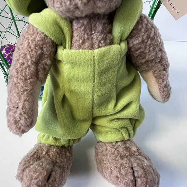 Plush toy rabbit wearing green overalls on a white background