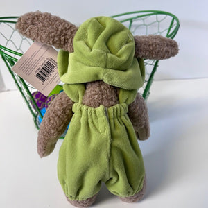 Plush toy rabbit with green outfit and brown ears on a white surface.