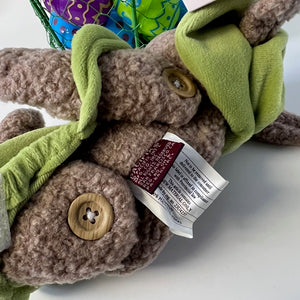 Plush toy with green straps and a label on a white background