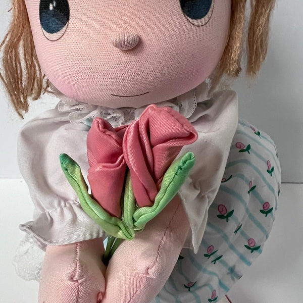 Stuffed toy holding a pink flower against a white background
