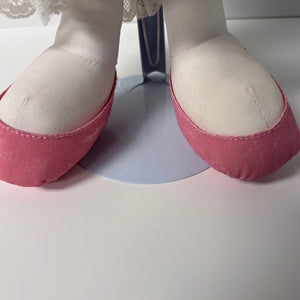 Close-up of pink and white fabric doll shoes on a white background