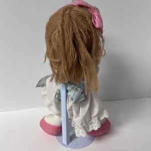 Doll with brown hair and a pink bow on a white background
