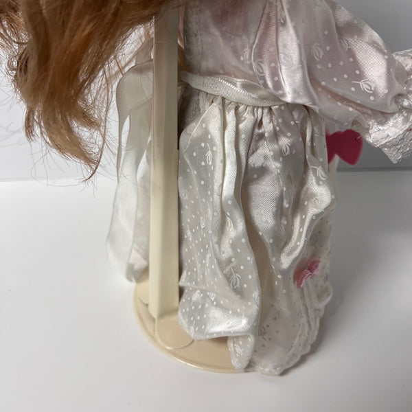 Close-up of a doll wearing a white outfit with pink hearts on a white background