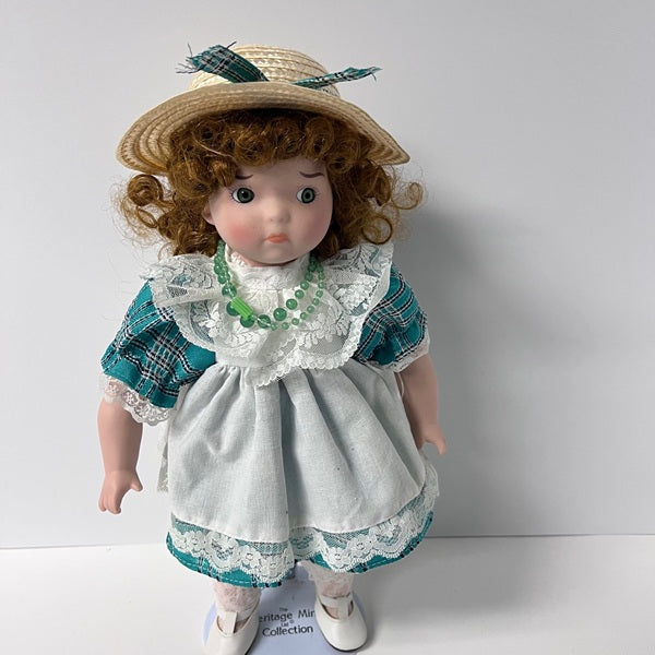 Vintage-style doll with a plaid dress and straw hat on a plain background