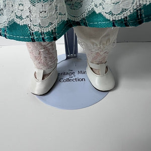 White shoes with a lace-up design on a white surface, with 'Heritage Miniature Collection' branding.