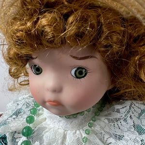 Close-up of a doll with curly hair, green eyes, and a white lace outfit.