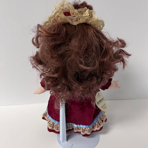 Doll with curly red hair and a red dress on a white background