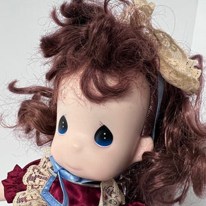 Close-up of a doll with red hair and blue eyes, wearing a red dress and blue ribbon.
