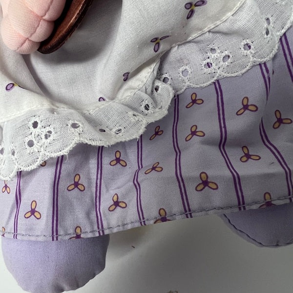 Close-up of a purple fabric with floral patterns and white lace trim.