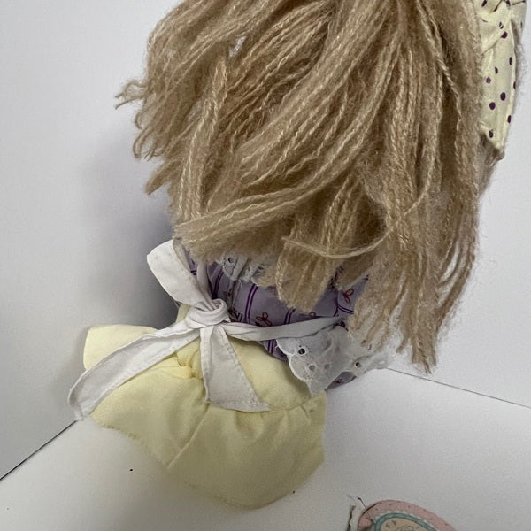 Vintage-style doll with blonde wig and yellow dress on a white background