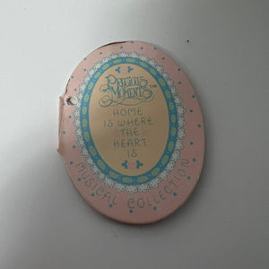 Round decorative item with text and a brand name on a light gray background