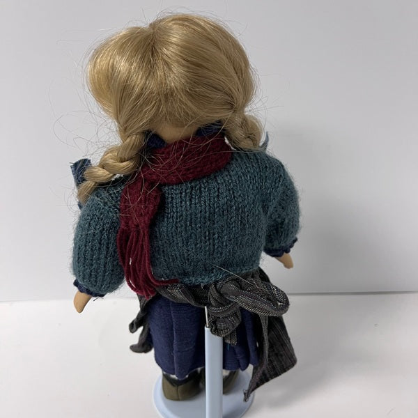 Doll with braided hair and a blue sweater on a white background