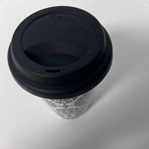 Black coffee cup with patterned sleeve on a white background