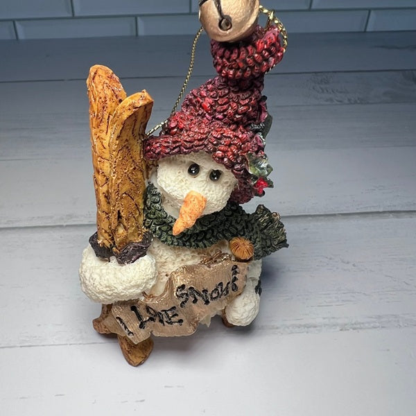 Decorative snowman figurine with a red hat and broom on a white wooden surface